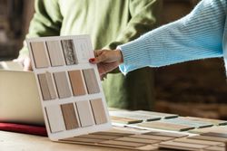 Anonymous woman choosing sample with carpenter in workshop