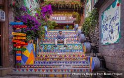 Male tourist sitting on colored stairs in the old city of Lijiang, China 4jzlR4