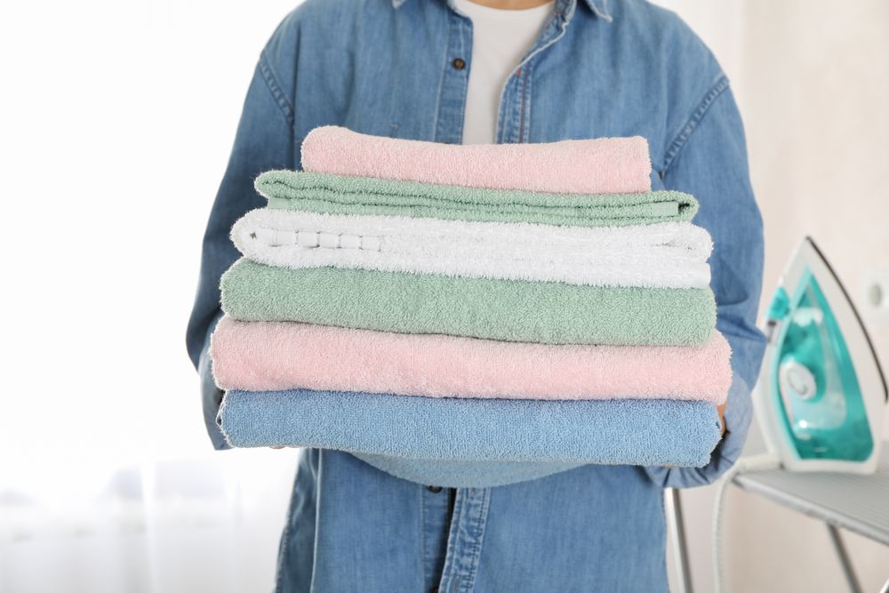 Young woman hold clean towels, close up and space for text