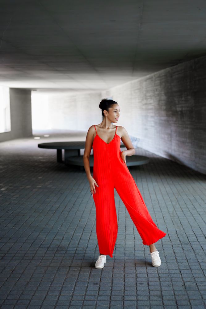 Elegant dance pose in a dynamic urban setting, featuring a vibrant red jumpsuit