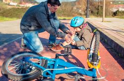 Father attending to son who fell off bike