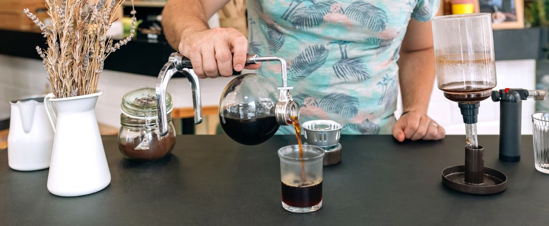 Banner of unrecognizable barista pouring specialty coffee from Japanese siphon coffee maker in glass