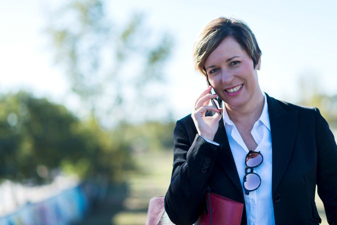 Happy woman standing outside speaking on phone