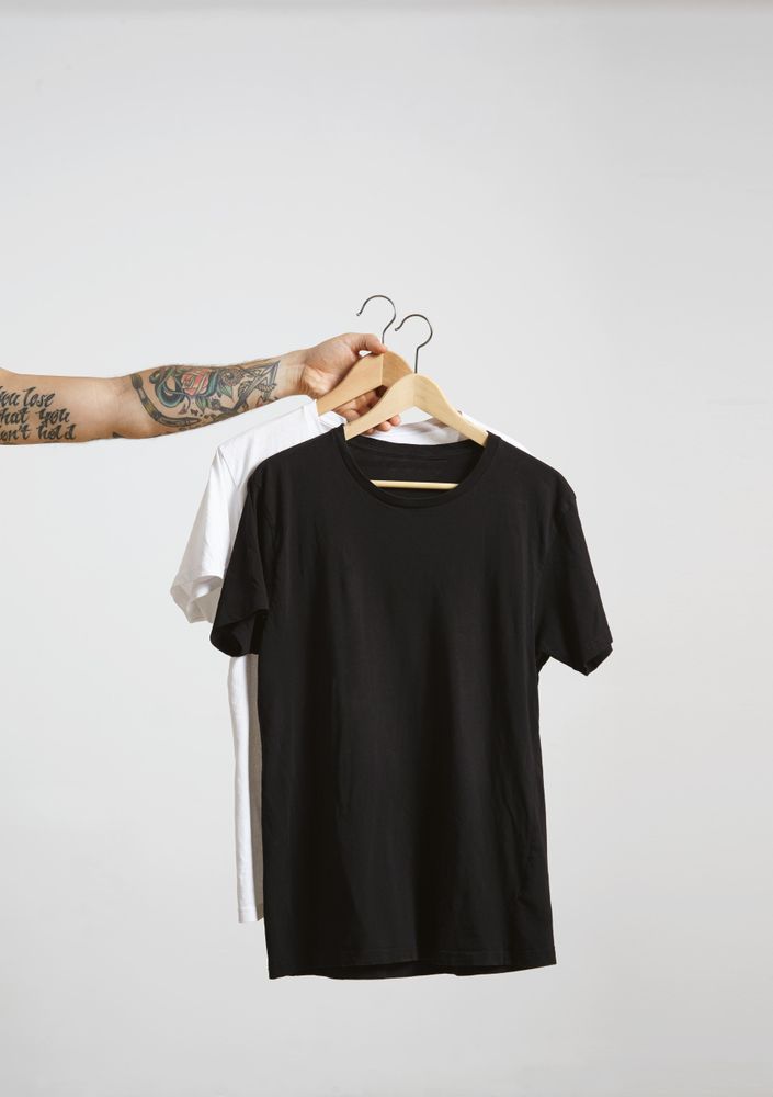 Arm holding two t-shirts on hanger