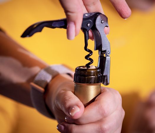 Opening a bottle of wine with a corkscrew.