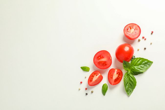 Flat lay composition with fresh cherry tomatoes, pepper and basil on plain background, space for text. Ripe vegetables
