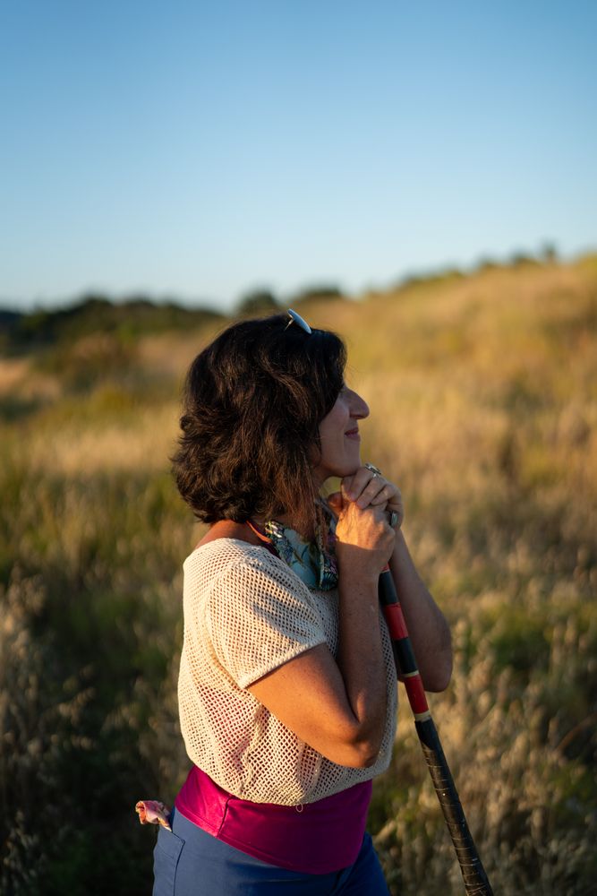 Side view portrait of woman leaning on a walking stick, looking out and smiling
