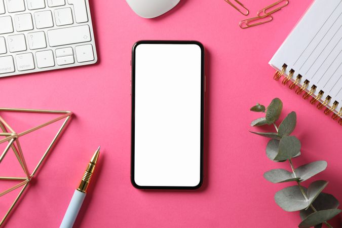 Workplace with phone with empty screen, top view