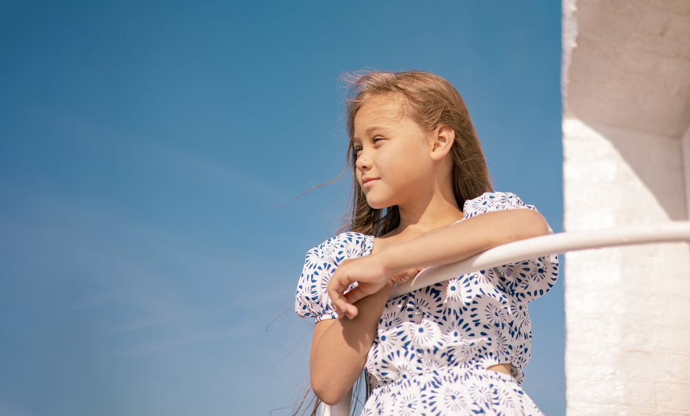 Girl in dress on the beach with long blond hair