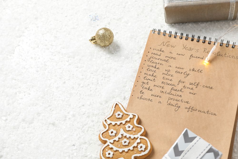Cookie, gift boxes and notepad with list on light background, space for text