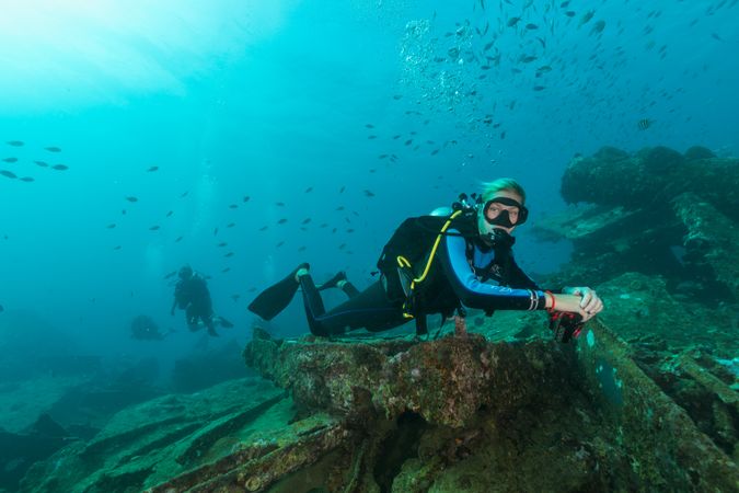 Scuba divers swimming underwater exploring wreckage
