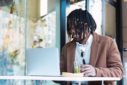 Serious Black man with espresso and glass of water in cafe