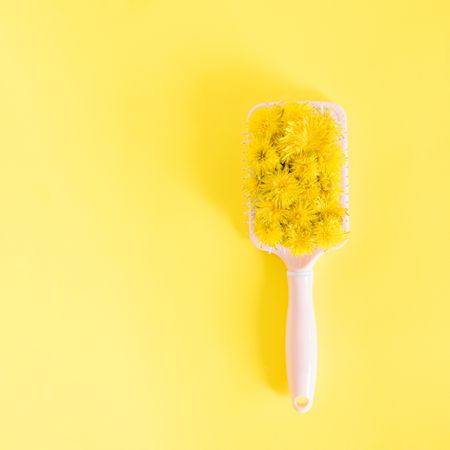 Hair brush with yellow spring flowers on bright yellow background