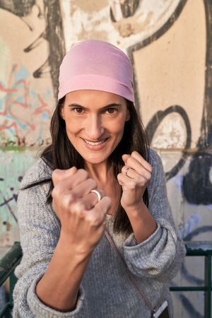 Smiling woman clenching fist for fighting against cance