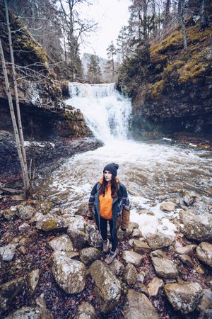 Woman standing at fast mountain river in forest