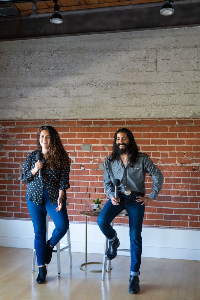 Two colleagues smiling while giving a talk