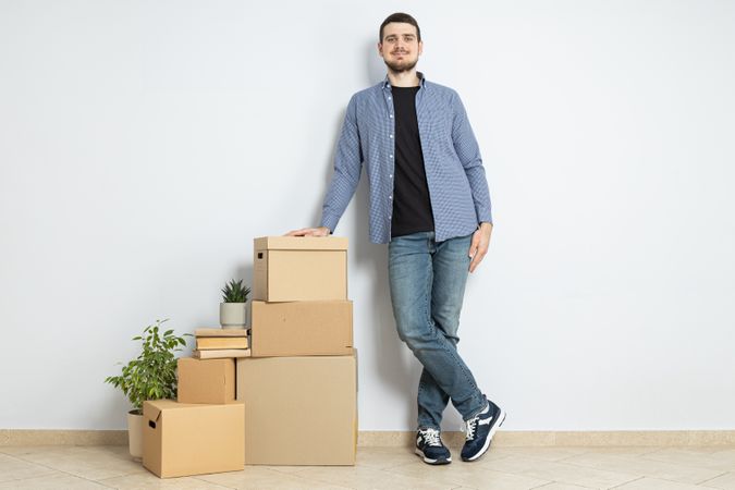 Moving concept, man with boxes leaning on boxes