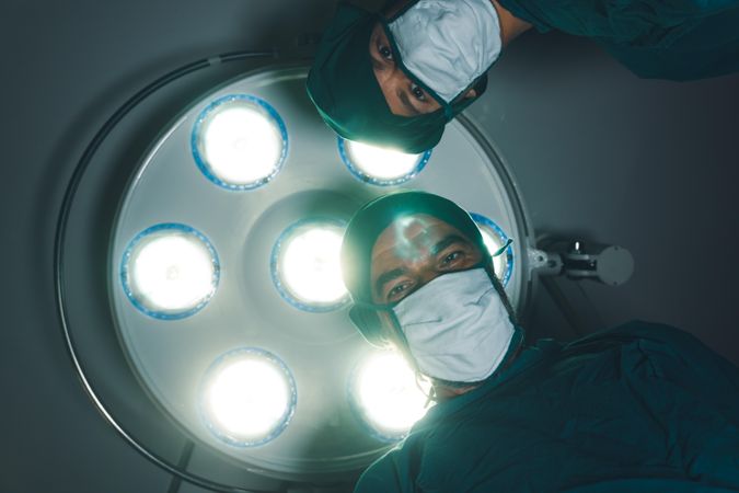 Two doctor looking down from light in a hospital’s operation room