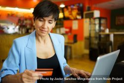 Female in trendy blue jacket sitting in cafe with laptop and credit card 4d8exQ