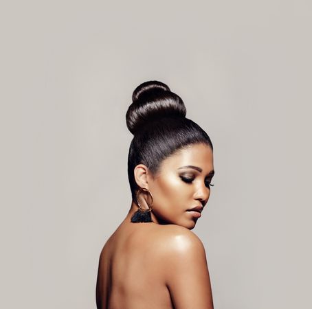 Elegant young woman with hair bun against grey background