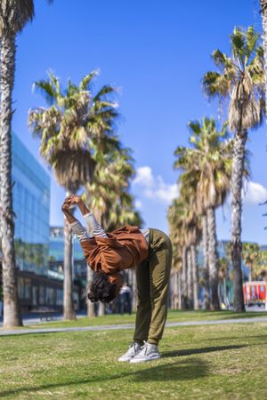 Black woman stretching back under the palms in a promenade