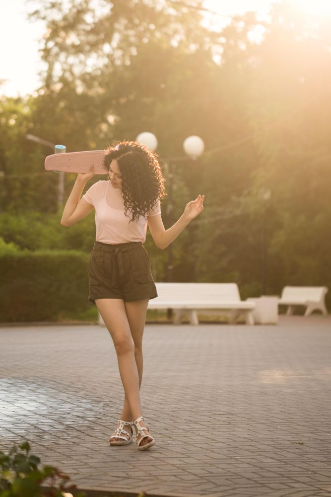 Teenager with pink skateboard behind her head