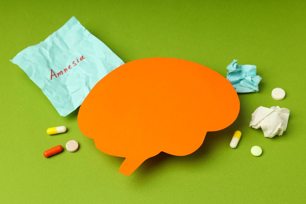 Orange paper cut out of brain on green background with pills and post it notes