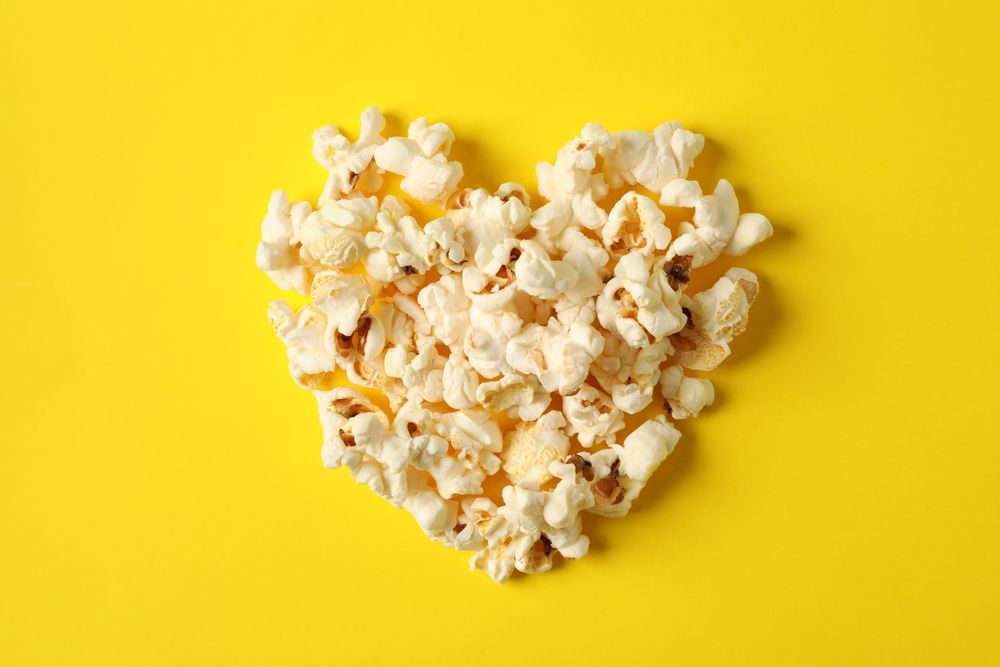 Flat lay composition with popcorn heart on yellow background, space for text
