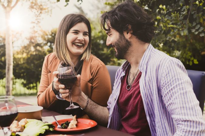 Cheerful couple in love on a date having fun toasting red wine in farmhouse restaurant