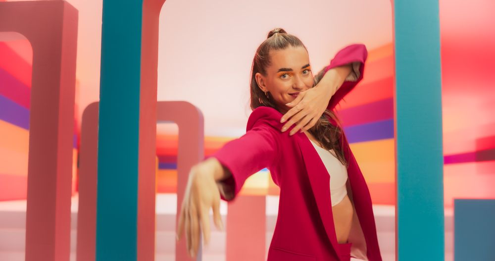 Medium Shot of an Woman in a Fashionable Outfit Moving her Hands Gracefully While Dancing and Looking at Camera. Female Dancer Performing Choreography in a Spacious Colorful Studio.