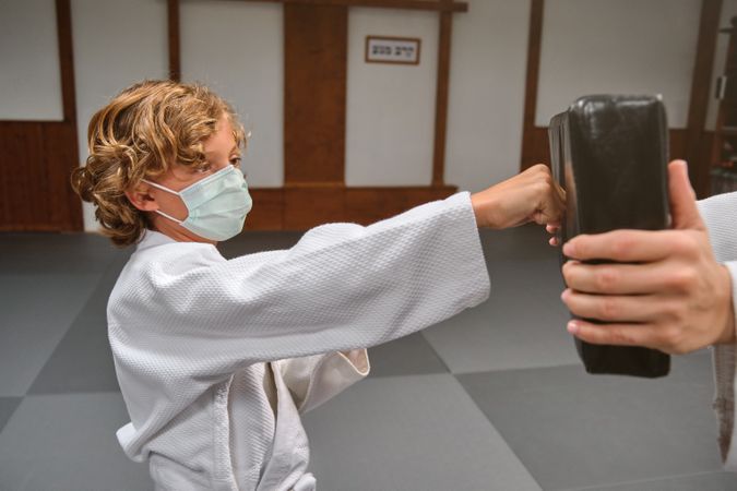 Boy in kimono practicing punches during training