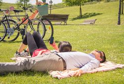 Woman using smartphone lying over man on the park