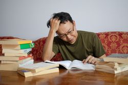 Asian young male reading book with frustrated gesture