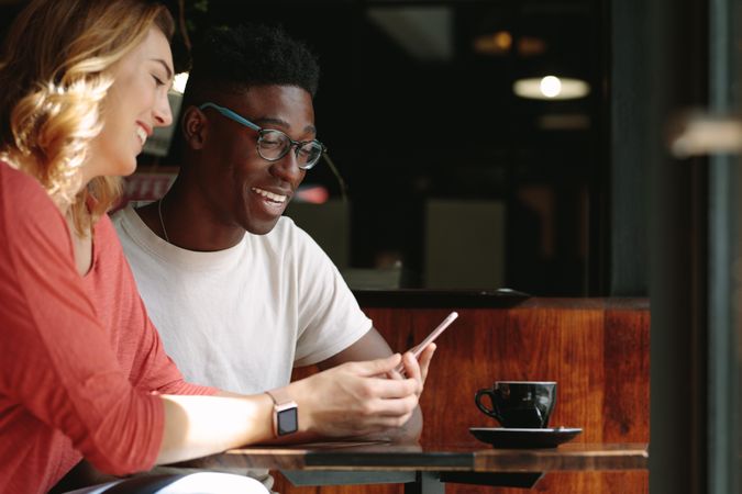 Man and woman sitting at a coffee table looking at a mobile phone