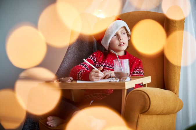 Boy in Santa hat writing on paper