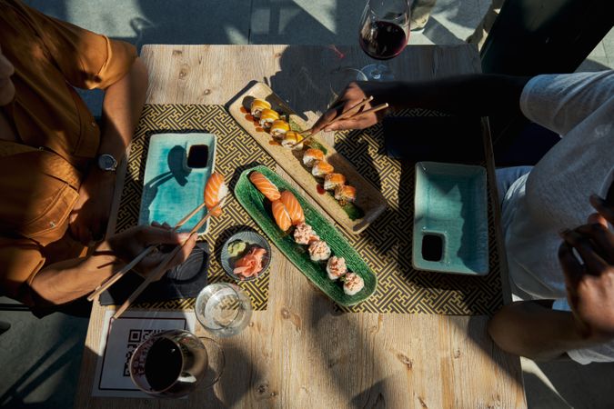 Crop friends eating sushi in cafe