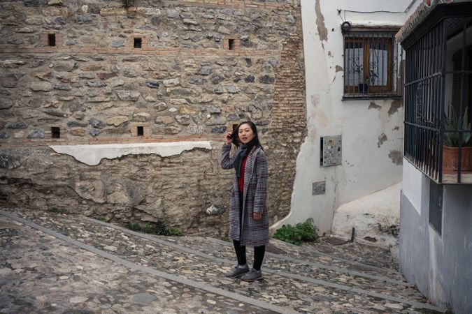 Asian female on aged cobblestone steps in city alley