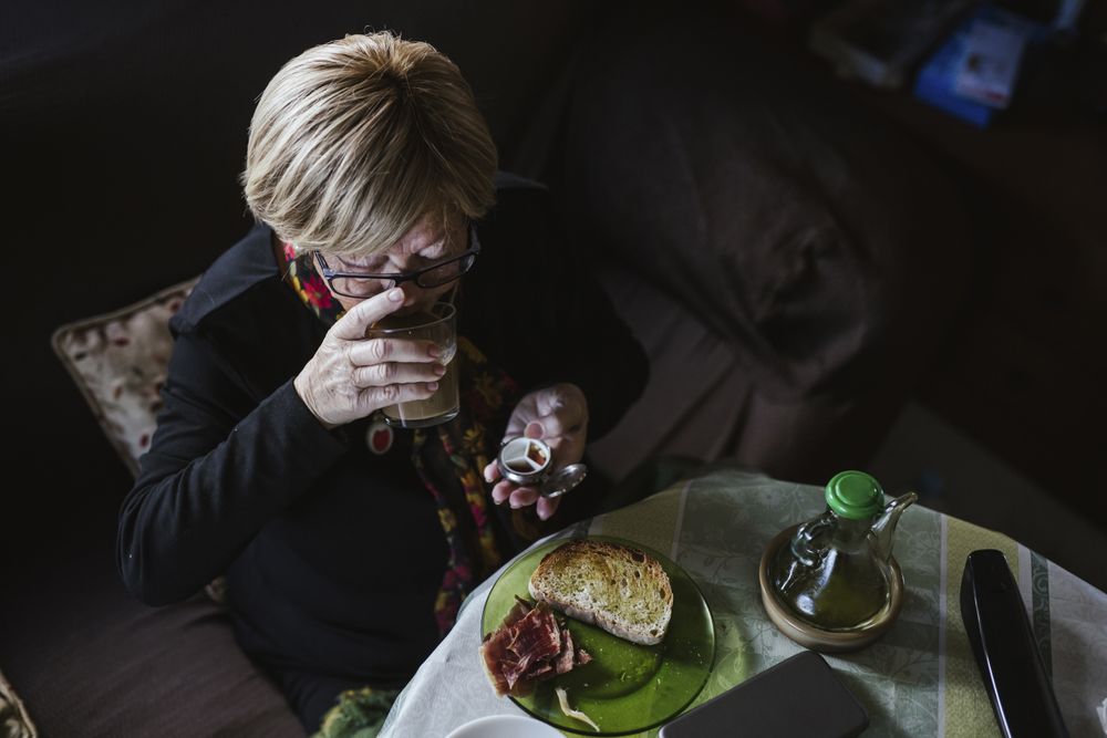 Older woman eating tablet from pill box