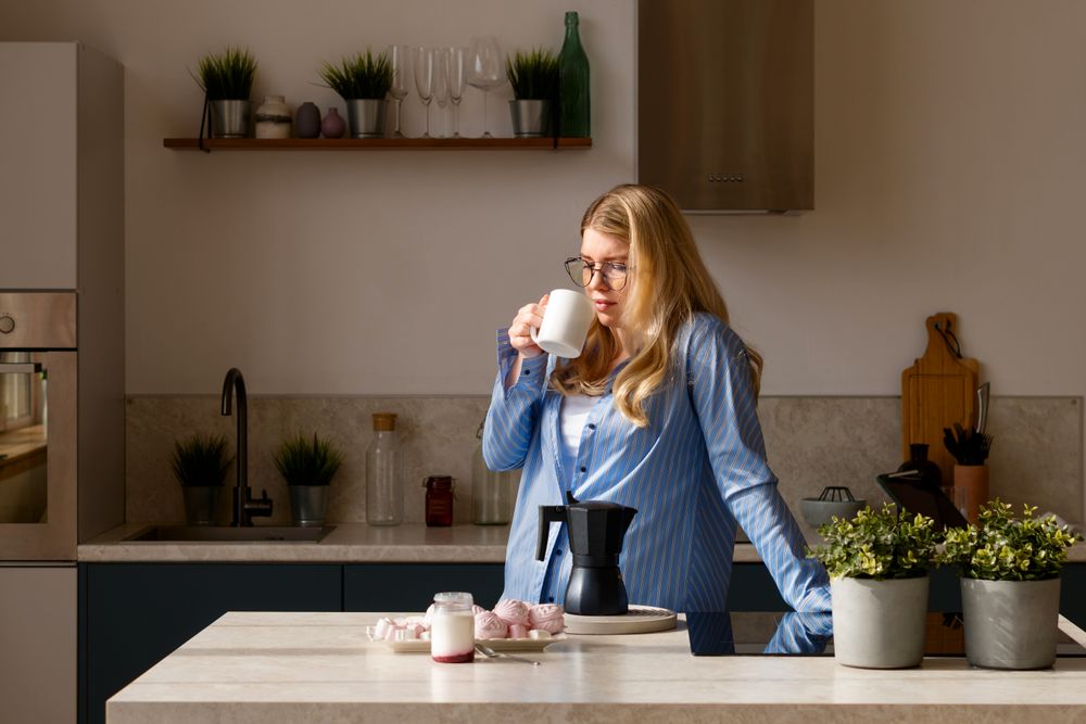 Woman sipping coffee in sunlight kitchen