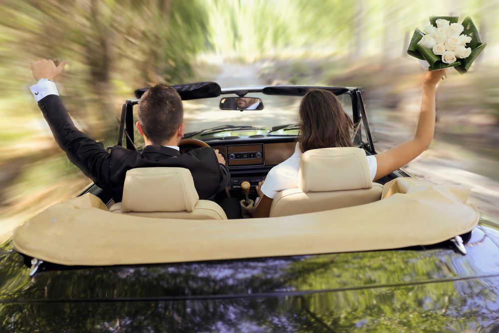 Back of couple speeding off in vintage car