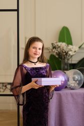 Girl holding gift box and smiling at birthday party.
