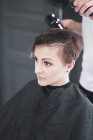 Hairdresser drying hair to woman