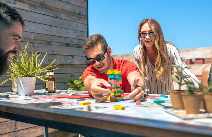 Concentrated man catching game piece next to colleagues on terrace