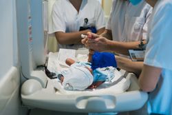 Team of professional doctors and nurses examining newborn baby at the hospital.