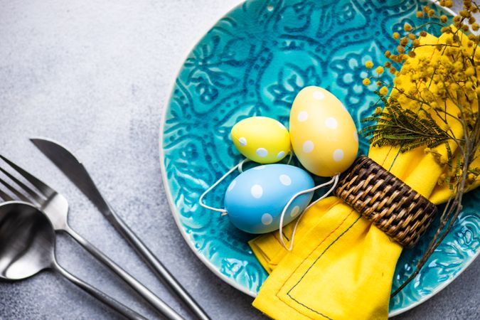 Easter table setting with yellow and blue decorative eggs on plate