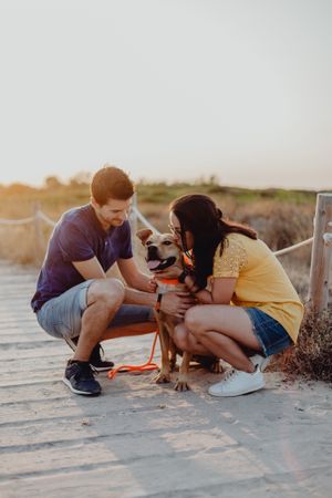 Happy adult couple petting dog at countryside