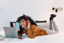 Cheerful Black female with laptop and smartphone