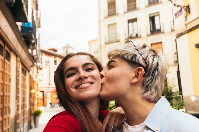 selfie photo of two young women kissing on the cheek