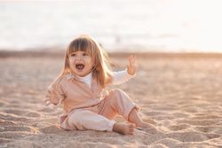 Girl making funny faces and sitting on sandy beach 0LJjV4