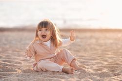 Girl making funny faces and sitting on sandy beach
